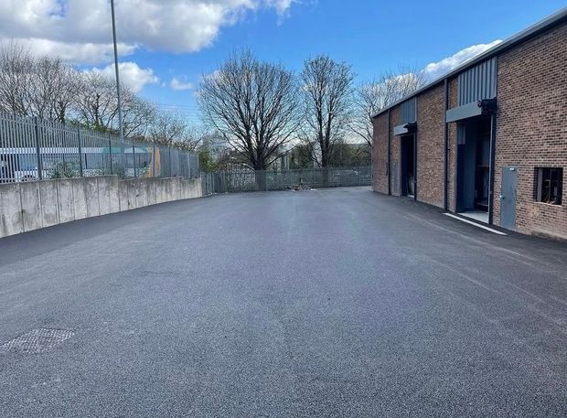 Freshly surfaced parking area outside a row of brick industrial units