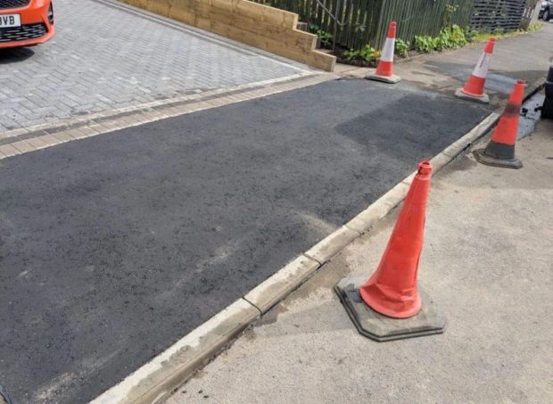 Newly laid tarmac dropped kerb crossing with the lowered kerb line alongside it