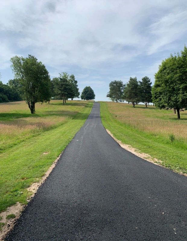 Resurfaced private access road running between grass verges